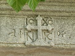 Kreuz mit Inschrift an einer Klostermauer